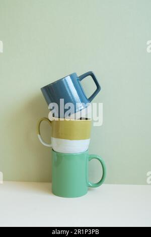 Stack of blue and green mug cups on white table. mint wall background. copy space Stock Photo