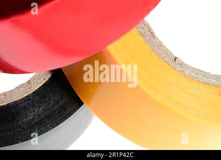 Extreme closeup partial view of three stacked multicolored yellow black red rolls of electrical tape duct tape tape on white background as a concept f Stock Photo