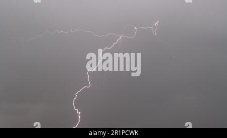 Lightning bolt in striking in the cloudy dark sky Stock Photo