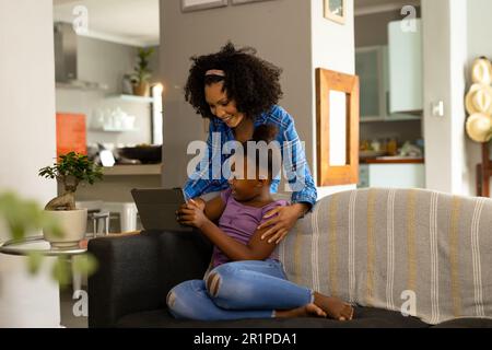 Happy african american mother and daughter looking at tablet together in living room at home Stock Photo