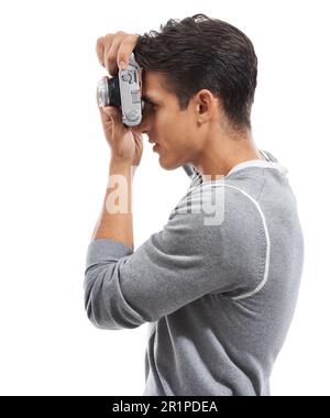 Life through a lens...Profile of a young man holding a camera and taking pictures against a white background. Stock Photo