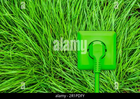 Green socket with power plug and cable on green grass Stock Photo