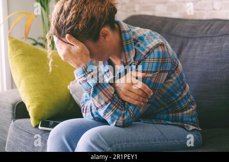 Sad tired young woman touching forehead having headache migraine or depression, upset frustrated girl troubled with problem feel stressed cover crying face with hand suffer from grief sorrow concept Stock Photo