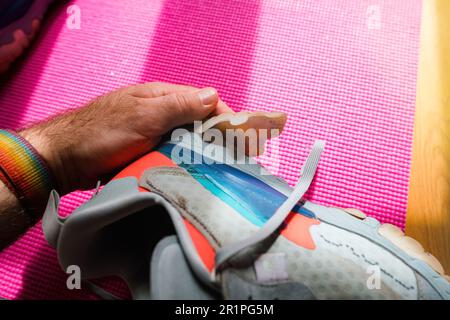 A man inspects a worn running shoe with his fingers, revealing the damaged sole peeling away Stock Photo