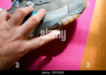 A man carefully inspects a ripped running shoe, his finger touching the worn fabric and sole of the luxury sport equipment. Stock Photo