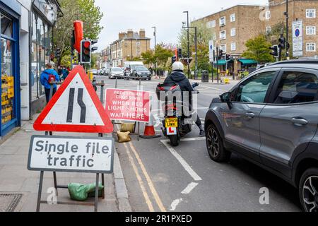 Temporary traffic lights and single file traffic sign at a junction in Stroud Green Road, North London, UK Stock Photo