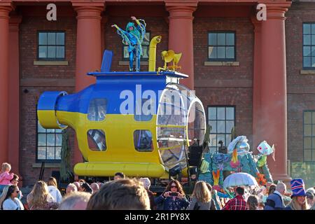 Beatles style yellow and blue , Ukraine flag coloured submarine DJ and dancer, Royal Albert Dock, Pier Head, Liverpool, Merseyside, England, UK,L3 4AF Stock Photo