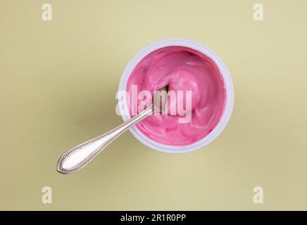 Pink red velvet flavour yogurt in plastic cup isolated on yellow pastel background with copy space Stock Photo