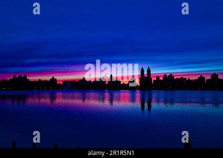 Sunset at Jacqueline Kennedy Onassis Reservoir, in New York City's Central Park silhouettes the iconic Central Park West skyline. Stock Photo