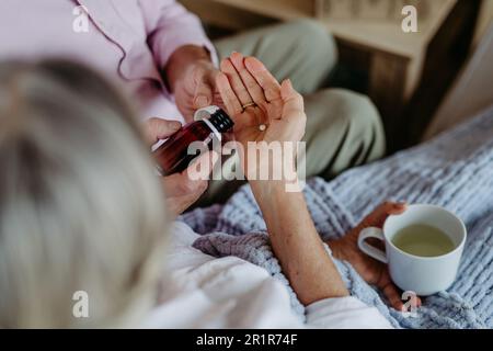 Close up of senior man giving medicines to his ill wife. Stock Photo