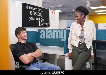 Two young college students relax in the library, talking and chatting Stock Photo