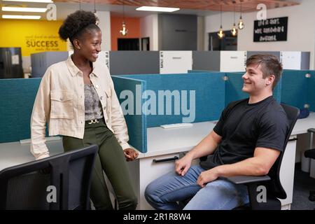 Two young college students relax in the library, talking and chatting Stock Photo
