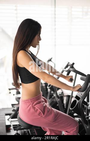 using gym machines a young latin woman wearing sportswear, active lifestyle for wellness and health, strength training Stock Photo