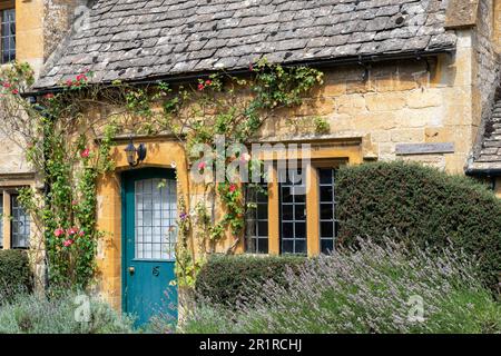 Broadway, UK-August 2022; Close up view of the flower overgrwon façade of a typical Cotswolds limestone cottage on High Street Stock Photo