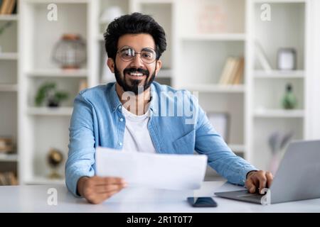 Handsome Indian Male Freelancer Working With Papers At Home Office Stock Photo