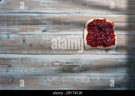 Slices of bread, sandwich with strawberry jam on old wooden table. Stock Photo