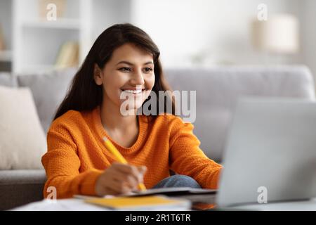 Positive young indian woman student attending webinar, using laptop Stock Photo