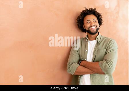 Successful cheerful confident young bearded african-american adult male entrepreneur businessman professional in casual wear standing with arms crossed and looking aside, curly guy isolated Stock Photo