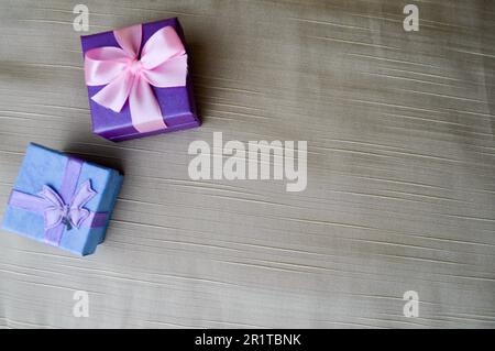 Gift, beautiful, festive boxes blue and purple with a pink bow and butterfly on a beige background. Stock Photo