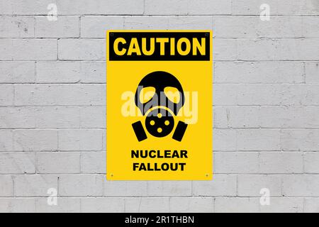 Yellow warning sign screwed to a brick wall to warn about a threat. In the middle of the panel, there is a gas mask symbol and the message is saying ' Stock Photo