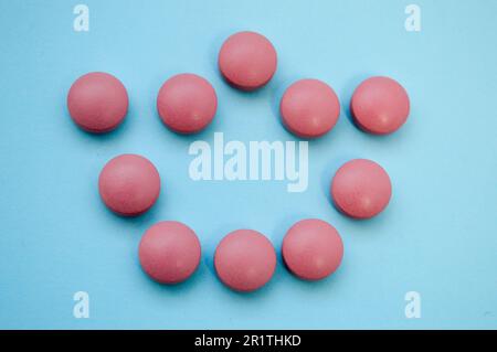 pink voluminous convex crown laid out in pills on a blue bright background. coronavirus infection. topical preparations for treating a person from a v Stock Photo