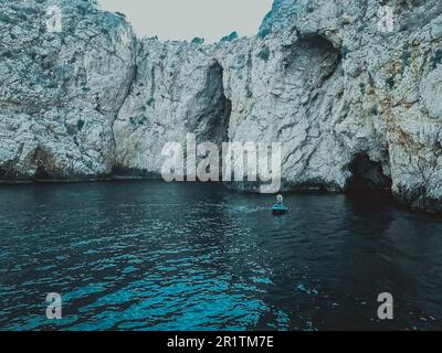 mountain in the sea. blue expanse of water. a mountain of sand, stones, a gorge in the vast sea. the ship swam between the rocks, natural beauty. Stock Photo