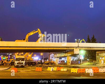 construction of a bridge in the city center. The overpass has cracked and is being repaired at night. construction equipment, cranes are standing arou Stock Photo