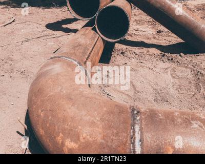 metal pipe lies on the ground. laying communications for residential buildings underground. conducting water. rusty, old, dirty metal pipe. Stock Photo