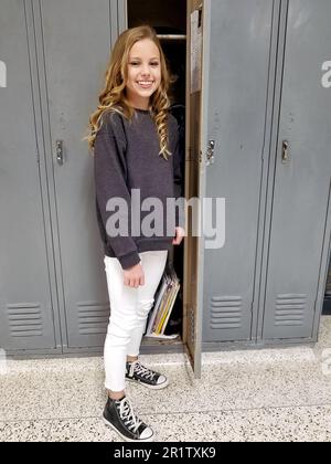 Blond Caucasian girl standing gray lockers in school hallway Stock Photo