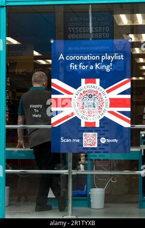 Notice in Poundland shop window celebrating King Charles III coronation advertising coronation playlist fit for a King. High Street Lincoln City, Linc Stock Photo