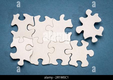 top view of white blank unfinished jigsaw puzzle on blue background, completing a task or solving a problem concept Stock Photo