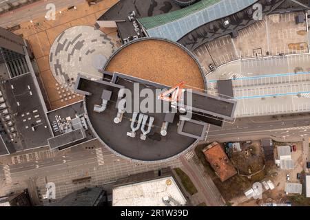 Drone photography of skyscraper rooftop, antenna on it and surrounding office buildings. Directly above Stock Photo