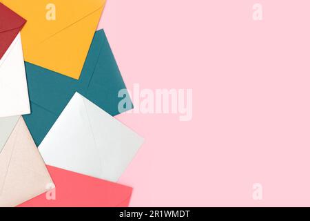 Multicolored envelopes scattered on a pink background. Creative concept with place for your design. Stock Photo