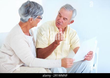 Mature couple during discussion. Happy mature couple discussing while reading letter at home. Stock Photo