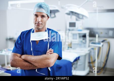 Theres no challenge I cant handle. A handsome doctor standing in scrubs in the operating theatre. Stock Photo