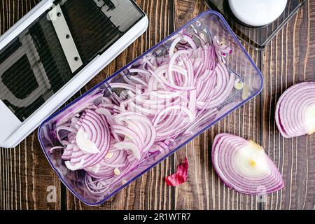 Red Onions Sliced Thinly with a Mandoline: Thinly sliced red onion and a mandoline viewed from directly above Stock Photo