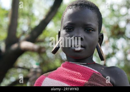 Omo Valley, Ethiopia â€“ 11.17.2022: Young woman from the Mursi tribe with large plates in her ears Stock Photo