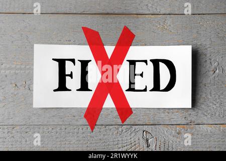 Card with optimistic word Fixed on grey wooden background, space for text. Letter X made of red adhesive tape Stock Photo