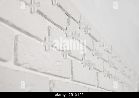 Decorative white bricks with tile leveling system on wall Stock Photo