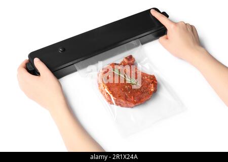Woman using sealer for vacuum packing and plastic bag with meat steak, rosemary on white background, closeup Stock Photo