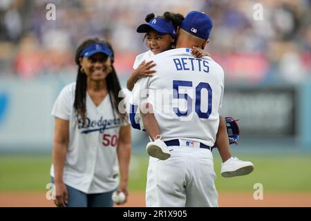 Kynlee Betts, center, greets her father, Los Angeles Dodgers right fielder Mookie  Betts (50), after she threw out the first pitch with her grandmother, Diana  Benedict, left, before a baseball game against