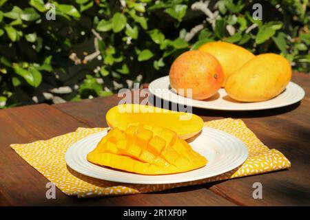 Plates with tasty mango on wooden table outdoors Stock Photo