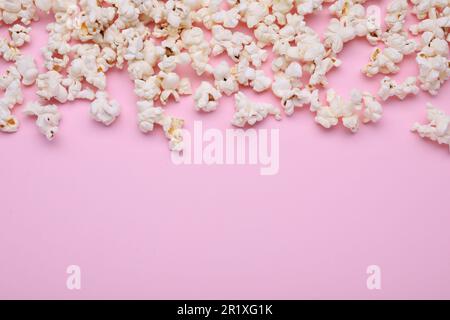 Tasty popcorn scattered on pink background, space for text Stock Photo