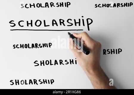 Man writing word SCHOLARSHIP on whiteboard, closeup Stock Photo