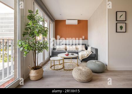 Stylish seating area with a terracotta color wall with a sofa and pouffes near the panoramic windows in the living room. The concept of a modern Stock Photo