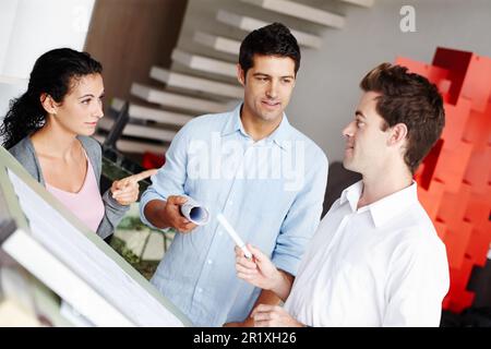 Sharing architectural ideas. Three talented architects discussing how they improve upon their blueprints. Stock Photo