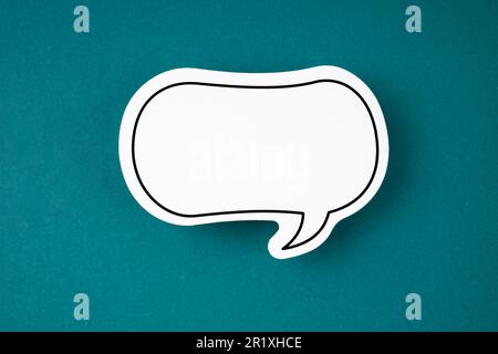 White speech bubble shaped post it note on green background with copy space. Stock Photo