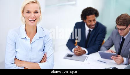 Find your place in the working world. Portrait of a confident businesswoman with arms crossed and colleagues in the background. Stock Photo