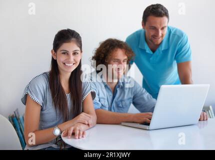 Were working on something big. three coworkers gathered around a laptop in the office. Stock Photo