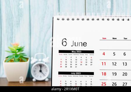 June 2023 Monthly desk calendar for 2023 year with alarm clock on blue wooden background. Stock Photo